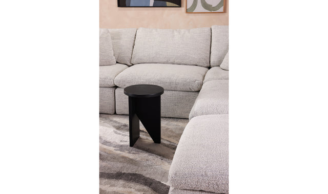 Table d'appoint en bois noir au design minimaliste pose sur tapis texture dans un interieur moderne.