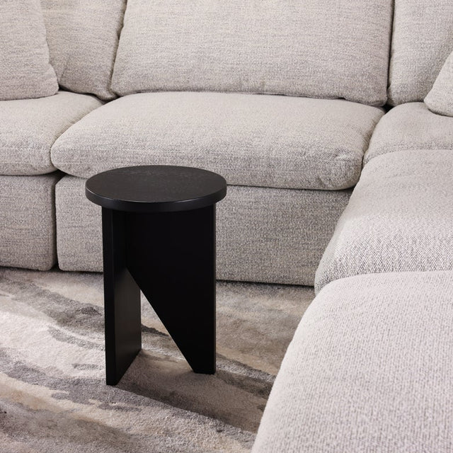 Table d'appoint en bois noir au design minimaliste pose sur tapis texture dans un interieur moderne.