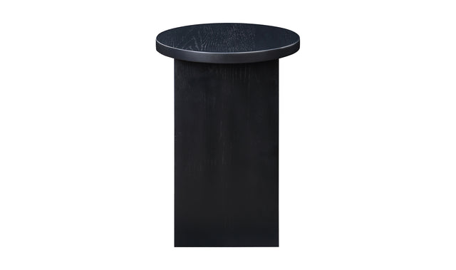 Table d'appoint en bois noir au design minimaliste pose sur tapis texture dans un interieur moderne.