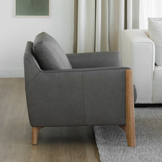 vue laterale d un fauteuil en cuir gris avec structure et pieds en bois clair.