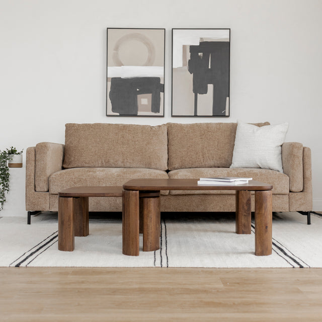 Tables basses gigognes en bois fonce devant canape beige sur tapis clair.