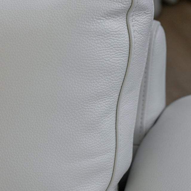 Image rapprochée d'un fauteuil en cuir crème avec structure en bois clair dans un salon lumineux.