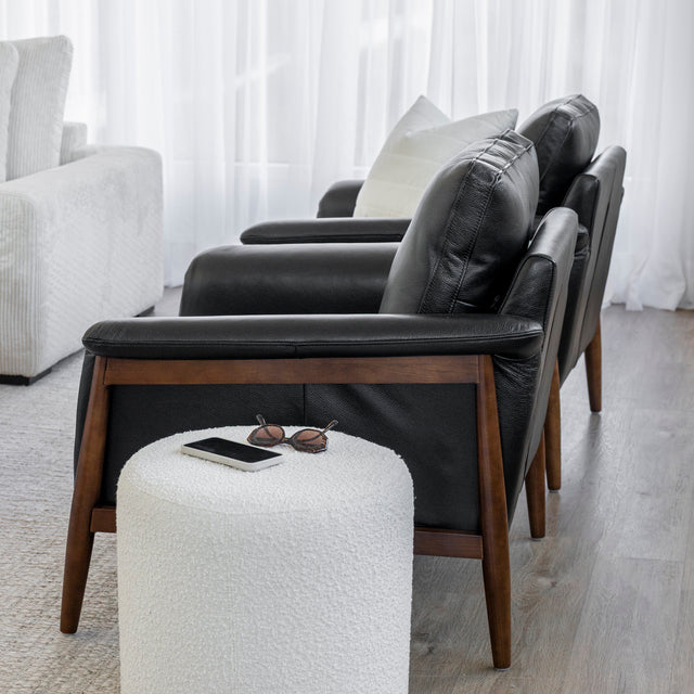 Fauteuil en cuir noir avec structure en bois dans un salon moderne.