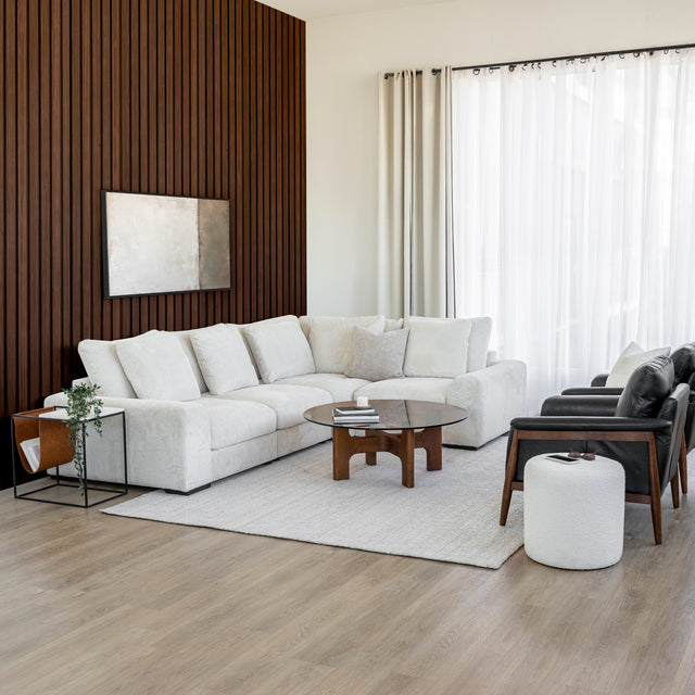 salon moderne avec canape d'angle crème, fauteuils en cuir noir et table basse en bois.