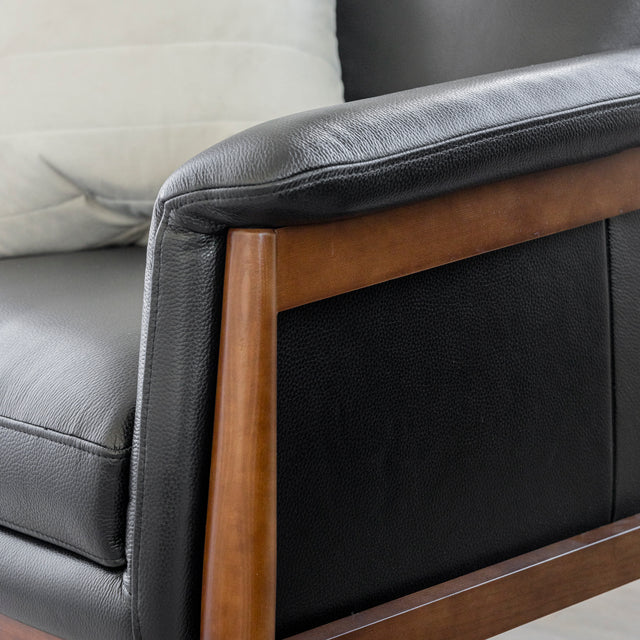 Image rapprochée d'un fauteuil en cuir noir avec structure en bois dans un salon moderne.