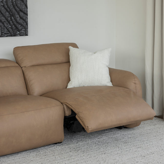 canape inclinable en cuir beige clair avec repose pieds ouvert et coussin blanc sur tapis clair.