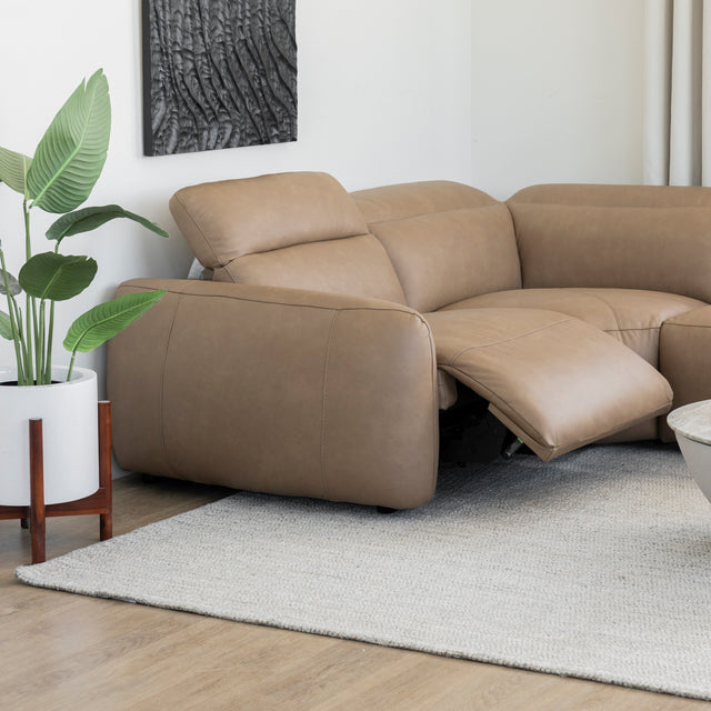 canape d angle inclinable en cuir beige clair avec repose pieds ouvert et plante decorative a cote.