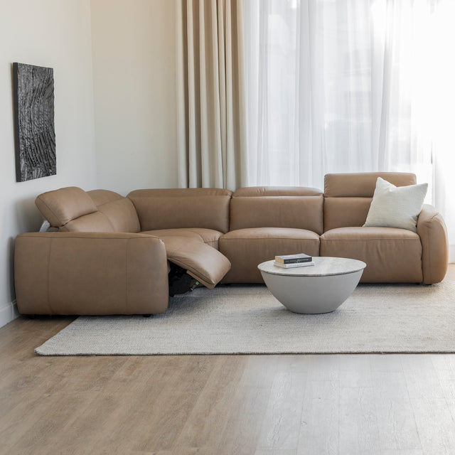 canape d angle moderne en cuir beige clair avec coussin creme dans un salon lumineux et minimaliste.