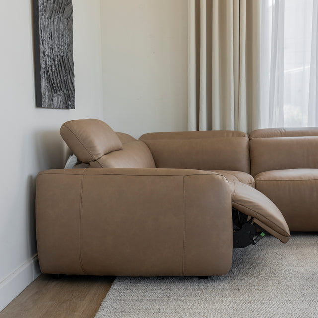 vue laterale du canape d angle inclinable en cuir beige clair avec repose pieds ouvert et appui tete ajuste.