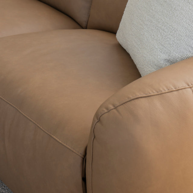 zoom sur l accoudoir et l assise du canape en cuir beige clair avec coussin texture creme.