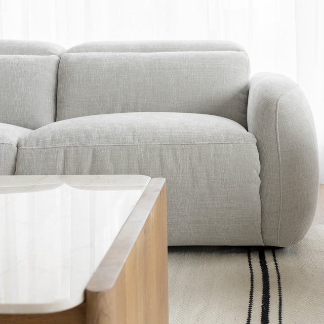 vue detaillee du canape en tissu gris clair avec accoudoir arrondi et table basse en bois clair.