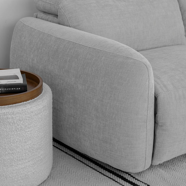 zoom sur l accoudoir du canape gris clair en tissu avec table d appoint ronde et livres.