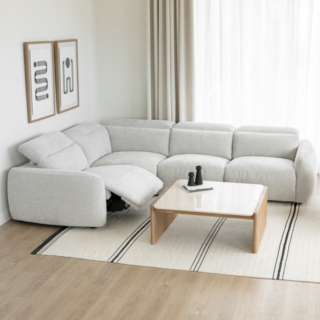 canape d angle inclinable en tissu gris clair avec repose pieds ouvert et table basse en bois clair.