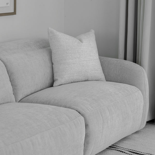 zoom sur le coin du canape gris clair en tissu avec coussin decoratif texture.