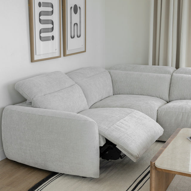 canape d angle gris clair en tissu avec dossier reglable et repose pieds ouvert.