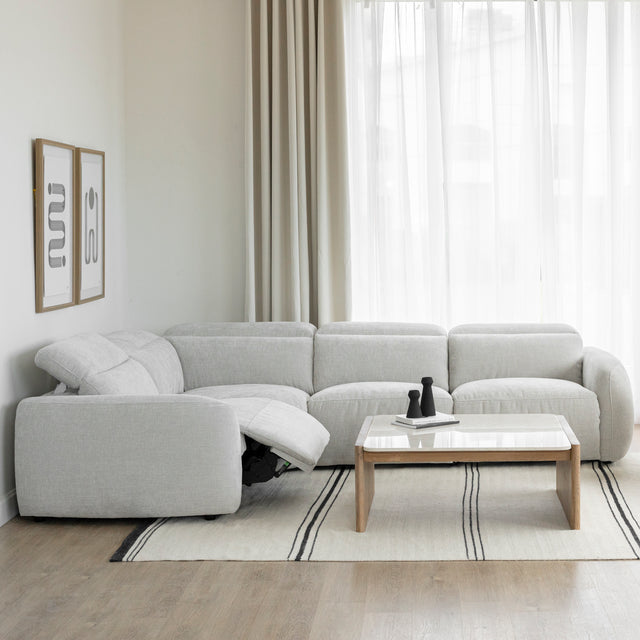 canape d angle inclinable en tissu gris clair avec repose pieds ouvert et table basse en bois clair.