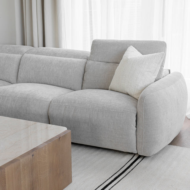 zoom sur le canape d angle en tissu gris clair avec coussin creme et table basse en bois clair.