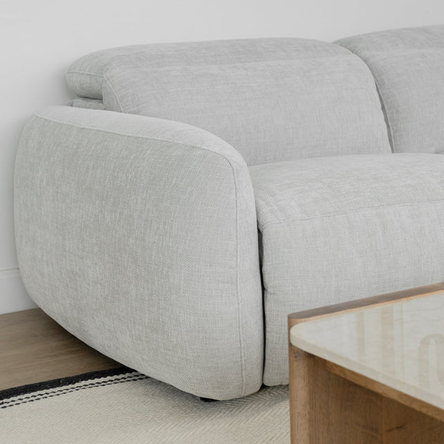 zoom sur l accoudoir du canape en tissu gris clair au design arrondi avec table basse en bois clair.