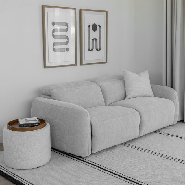 canape gris clair deux places en tissu avec coussin decoratif et table d appoint ronde.