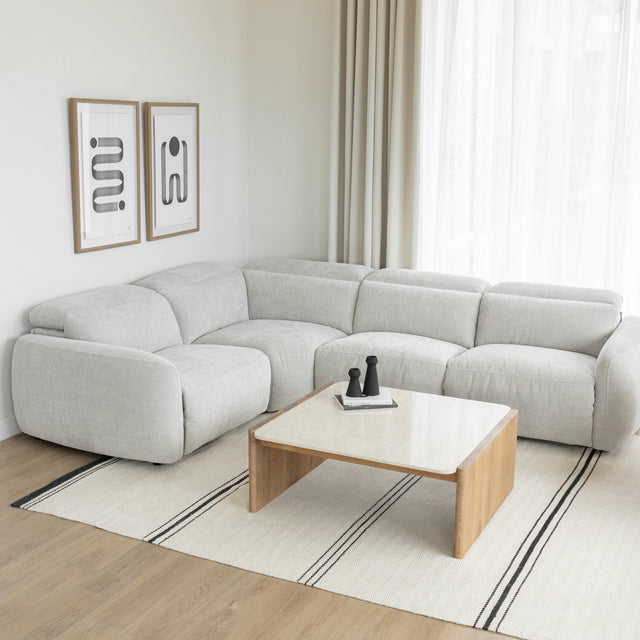 canape d angle gris clair moderne avec table basse en bois et tapis clair a rayures.