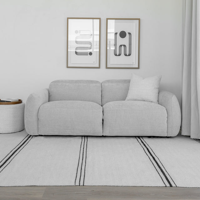 canape gris clair deux places en tissu avec coussin decoratif et table d appoint ronde.