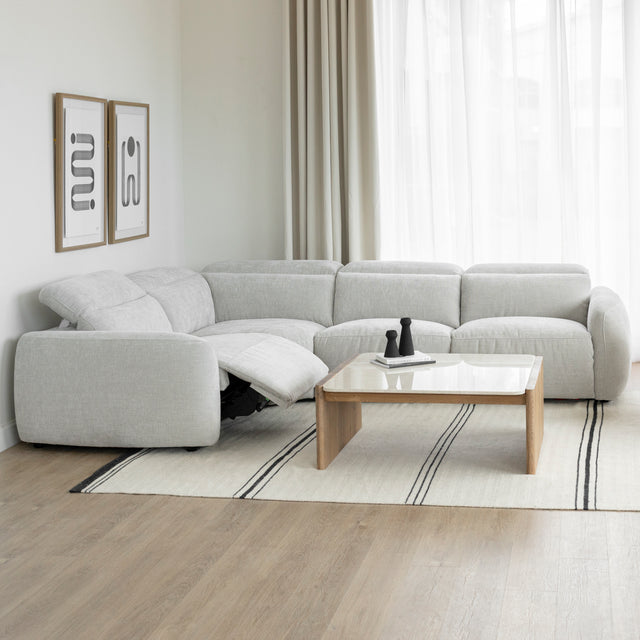 canape d angle inclinable en tissu gris clair avec repose pieds ouvert et table basse en bois clair.