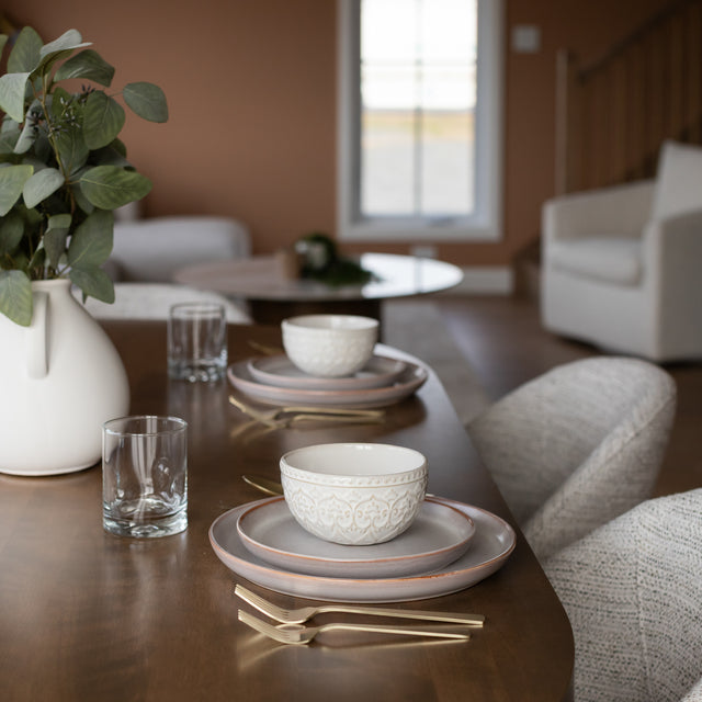table en bois avec vaisselle en ceramique blanche et couverts dorés dans une salle a manger moderne.