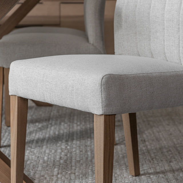 chaise de salle a manger avec assise rembourree en tissu beige clair et pieds en bois naturel sur tapis tisse.