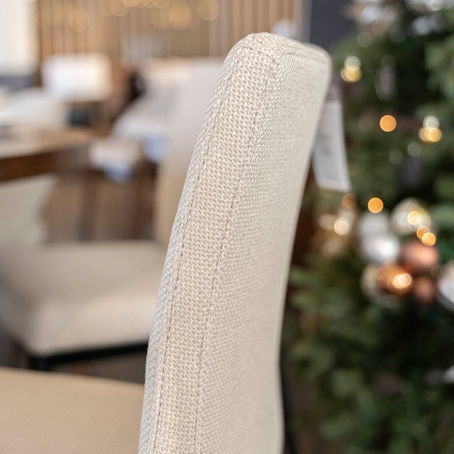 chaise moderne en tissu beige avec pattes noires.