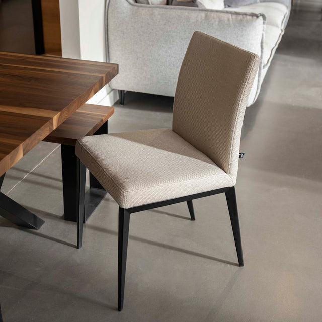 chaise moderne en tissu beige avec pattes noires.
