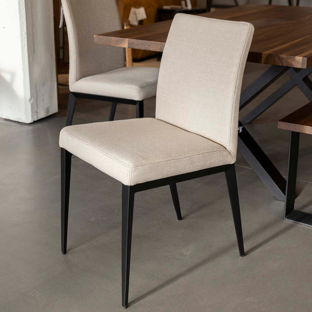 chaise moderne en tissu beige avec pattes noires.