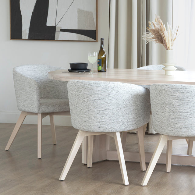 Chaise moderne en tissu crème avec pieds en bois clair dans une salle a manger minimaliste.
