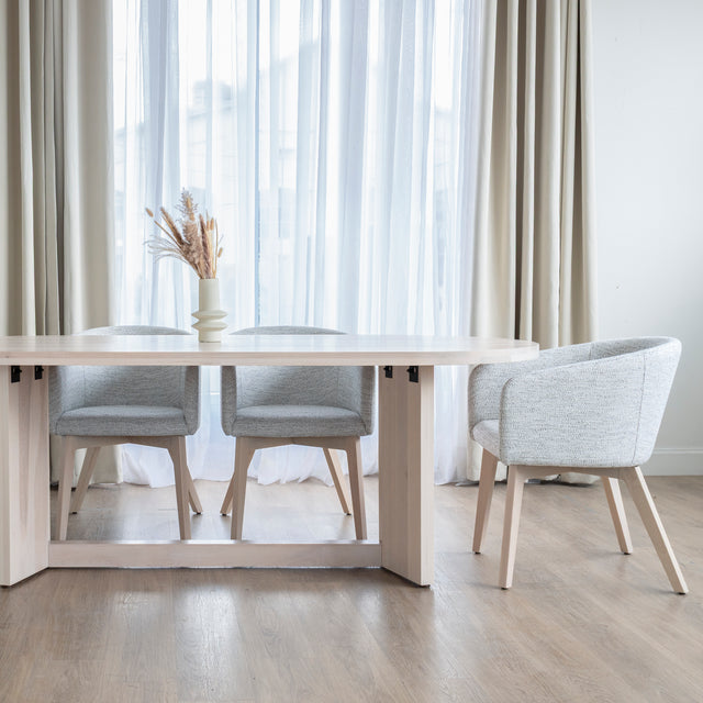 Chaise moderne en tissu crème avec pieds en bois clair dans une salle a manger minimaliste.