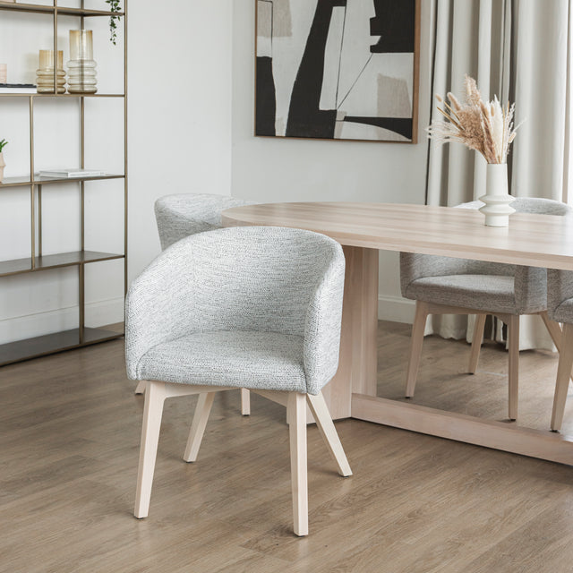 Chaise moderne en tissu crème avec pieds en bois clair dans une salle a manger minimaliste.