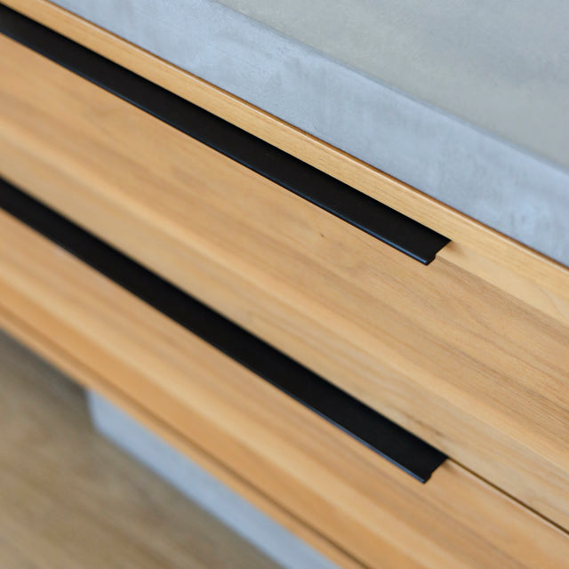 Image rapprochée d'un Meuble TV moderne en bois de noyer et beton gris avec tiroirs et etageres ouvertes.