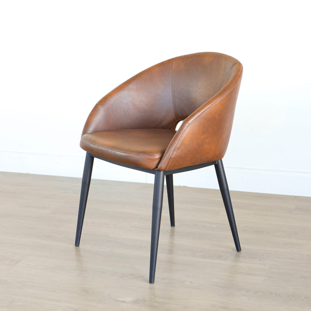 Chaise moderne en cuir cognac avec dossier incurvé et pieds noirs élegants.