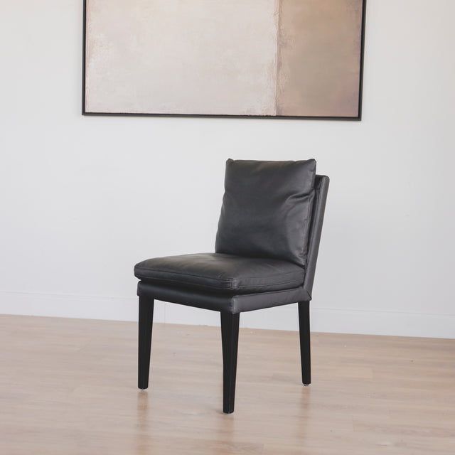 chaise en cuir noir avec coussins rembourrés et pieds en bois sombre.