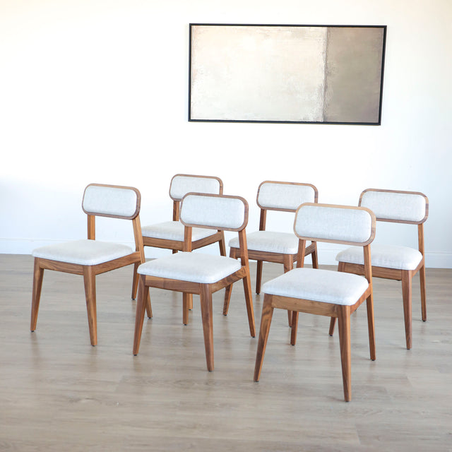 Lot de six chaises en bois de noyer avec assise et dossier rembourres en tissu beige.