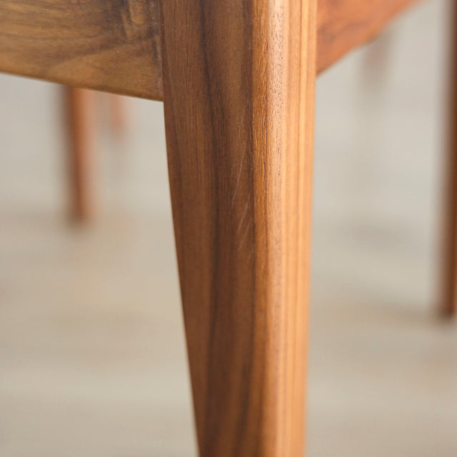 image rapprochée d'une chaise en bois de noyer avec assise et dossier rembourres en tissu beige.
