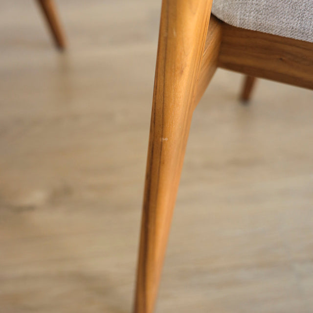 image rapprochée d'une chaise en bois de noyer avec assise et dossier rembourres en tissu beige.