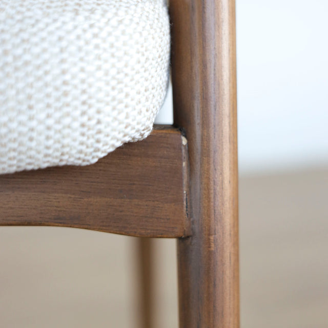 Image rapprochée d'une patte en bois d'un lot de trois chaises style scandinave avec structure en bois et assise beige rembourree.