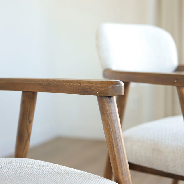 Image rapprochée d'un appuie bras en bois d'un lot de trois chaises style scandinave avec structure en bois et assise beige rembourree.