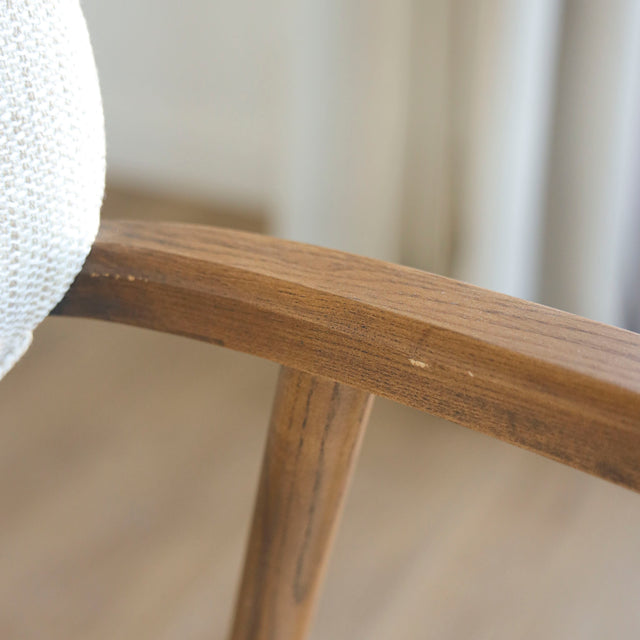 Image rapprochée d'un appuie bras en bois d'un lot de trois chaises style scandinave avec structure en bois et assise beige rembourree.