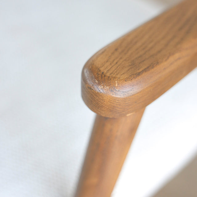 Image rapprochée d'un appuie bras en bois d'un lot de trois chaises style scandinave avec structure en bois et assise beige rembourree.