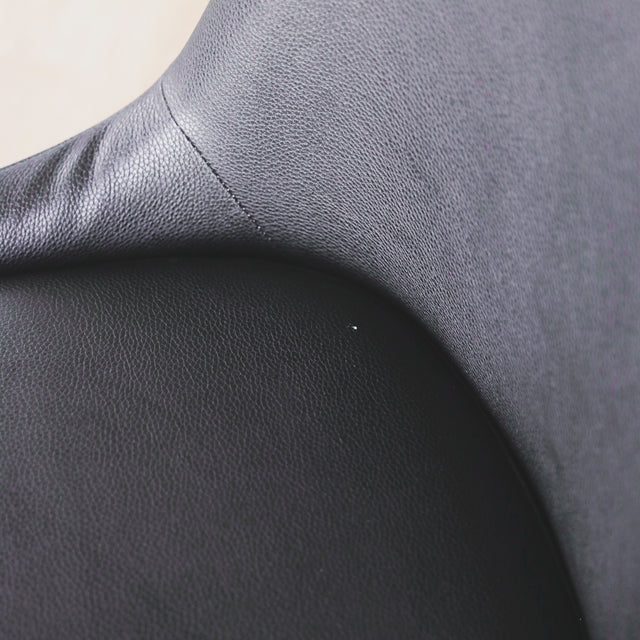 image rapprochée d'une chaise contemporaine en cuir végane noir avec design incurve et pieds assortis.