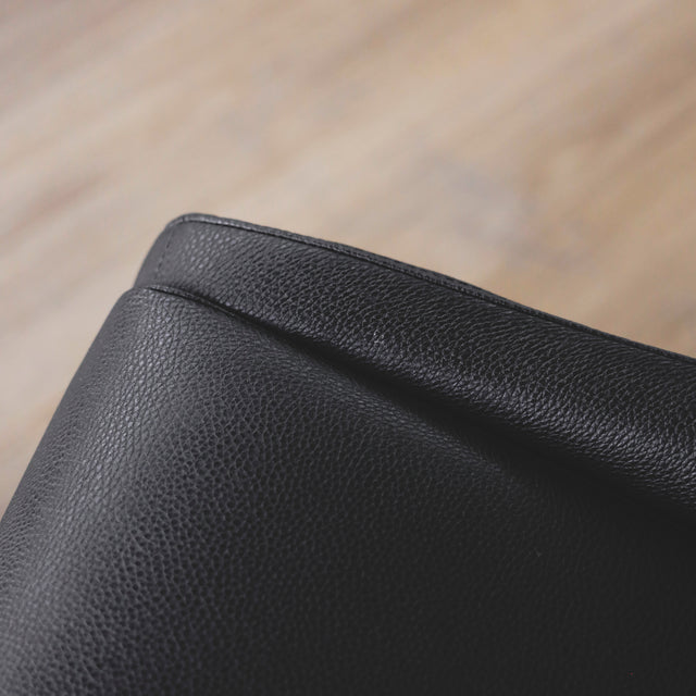 image rapprochée d'une chaise contemporaine en cuir végane noir avec design incurve et pieds assortis.