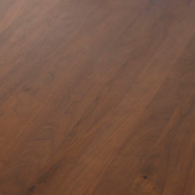 Image rapprochée d'une table ronde en noyer massif avec pied central croise au design contemporain.