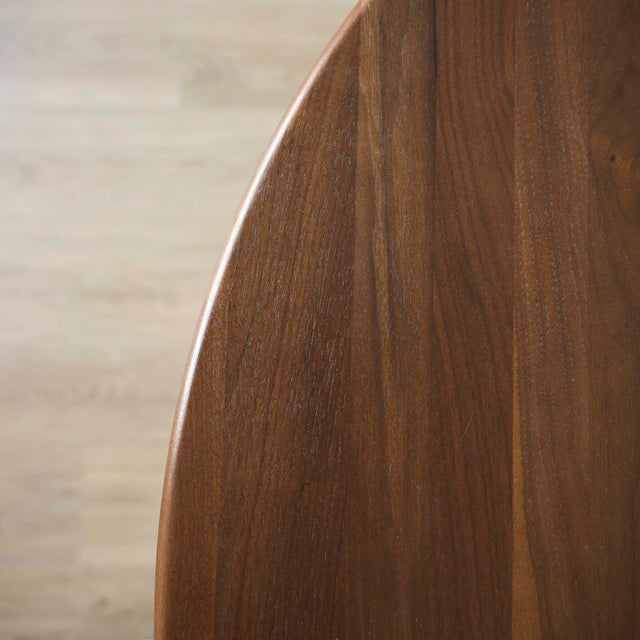 Image rapprochée d'une table ronde en noyer massif avec pied central croise au design contemporain.