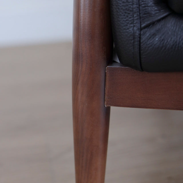 Image rapprochée d'un Fauteuil en cuir noir avec structure en bois style moderne.