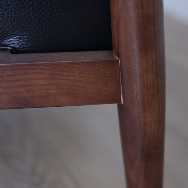 Image rapprochée d'un Fauteuil en cuir noir avec structure en bois style moderne.